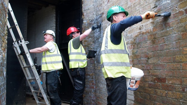 National Trust volunteers applying Stormdry Masonry Protection Cream to the brick buttress walls of the entrance to one of the Wanstone magazines